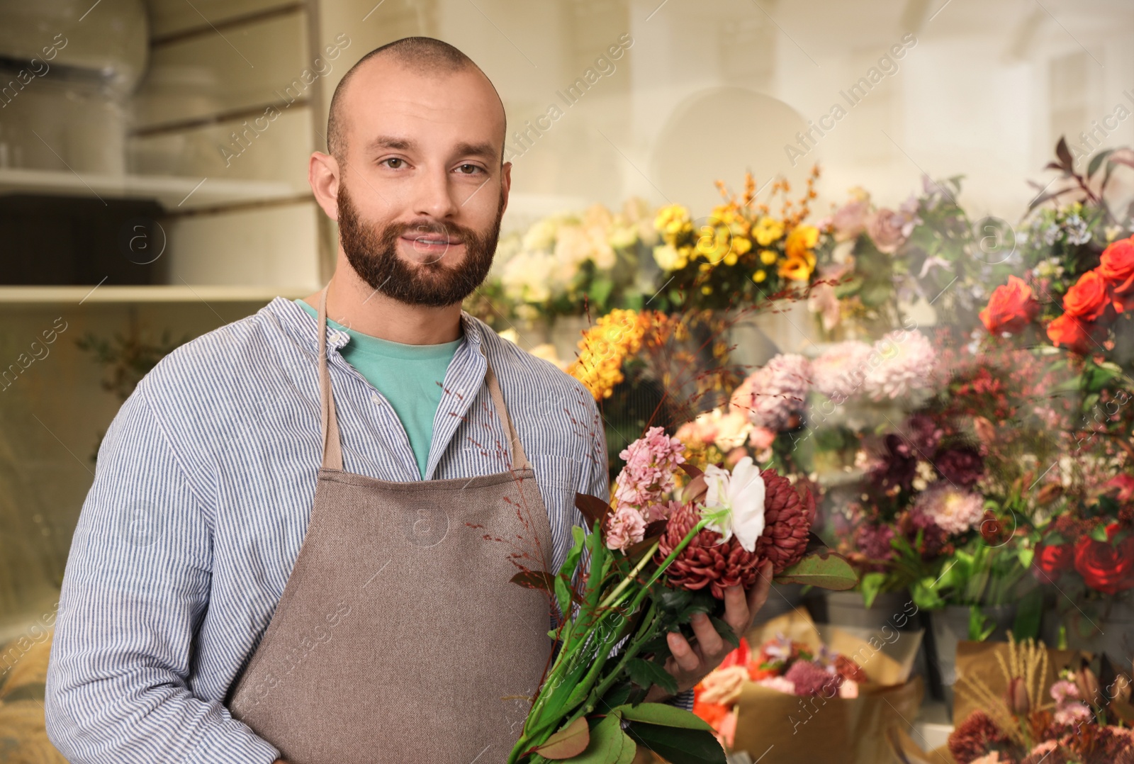 Photo of Professional florist with bouquet of fresh flowers in shop