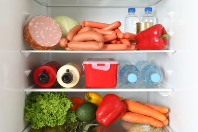 Photo of Open refrigerator with many different products, closeup