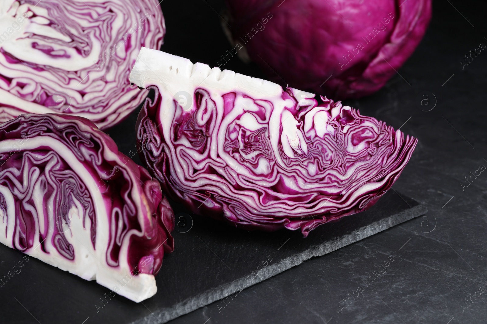 Photo of Closeup view of tasty fresh cut red cabbages on black table