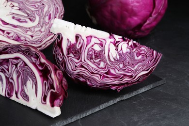Photo of Closeup view of tasty fresh cut red cabbages on black table