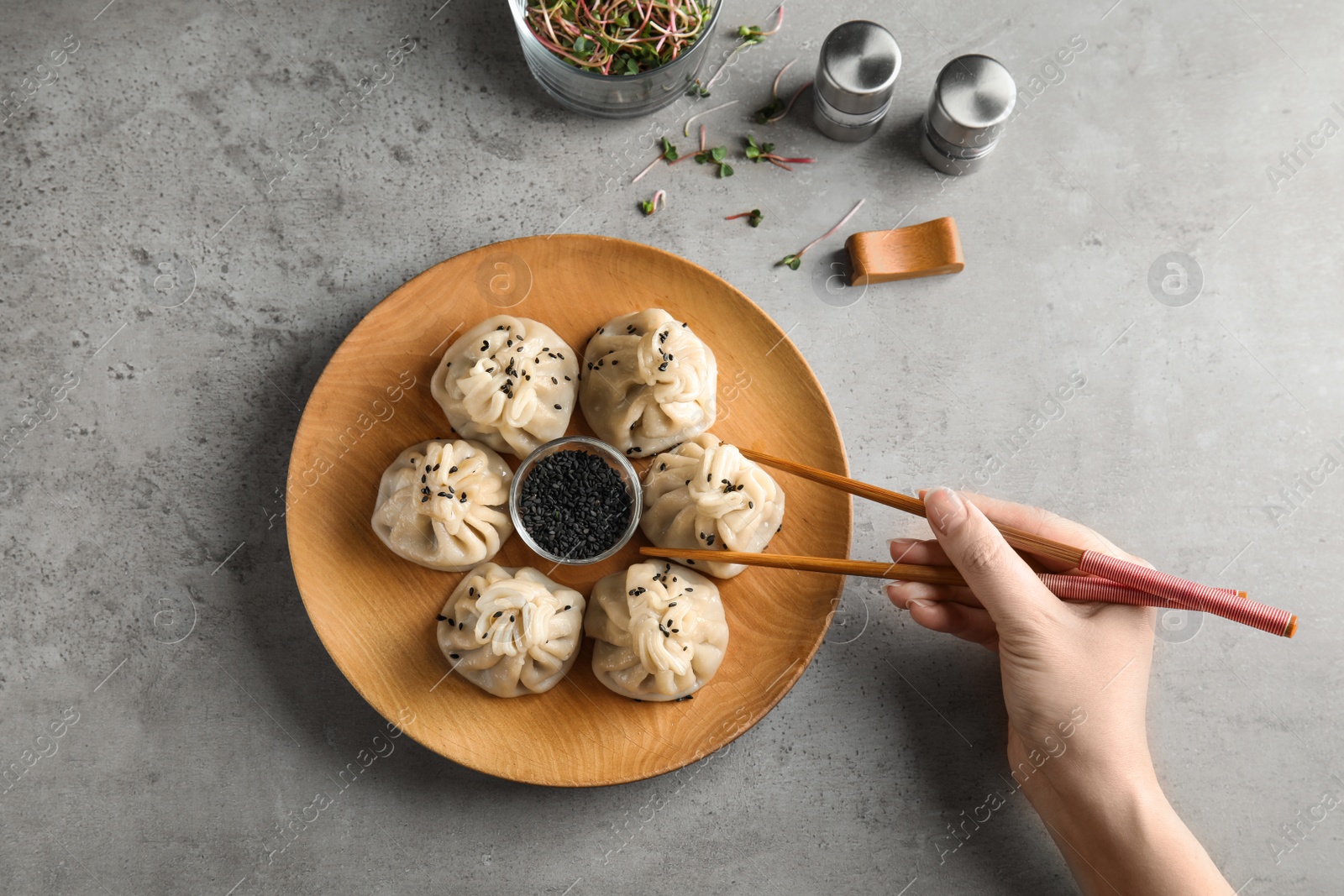 Photo of Woman eating tasty baozi dumplings at table, top view