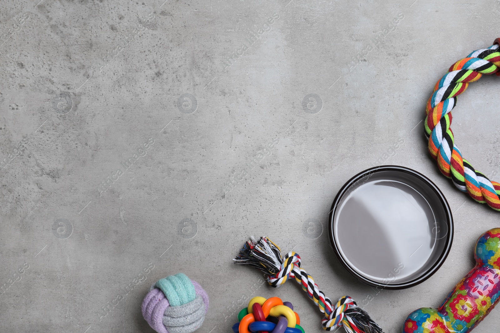 Photo of Flat lay composition with different pet toys and feeding bowl on grey background, space for text