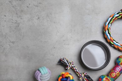 Flat lay composition with different pet toys and feeding bowl on grey background, space for text