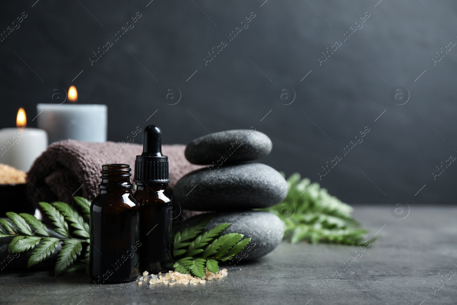 Photo of Spa composition with aroma oil on grey table, space for text