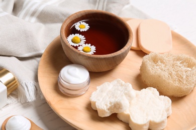 Photo of Chamomile flowers and different cosmetic products on white table, closeup