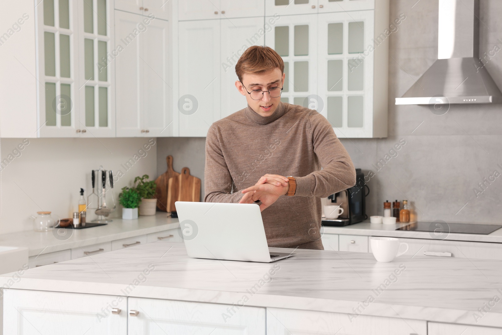 Photo of Emotional young man checking time in kitchen. Being late