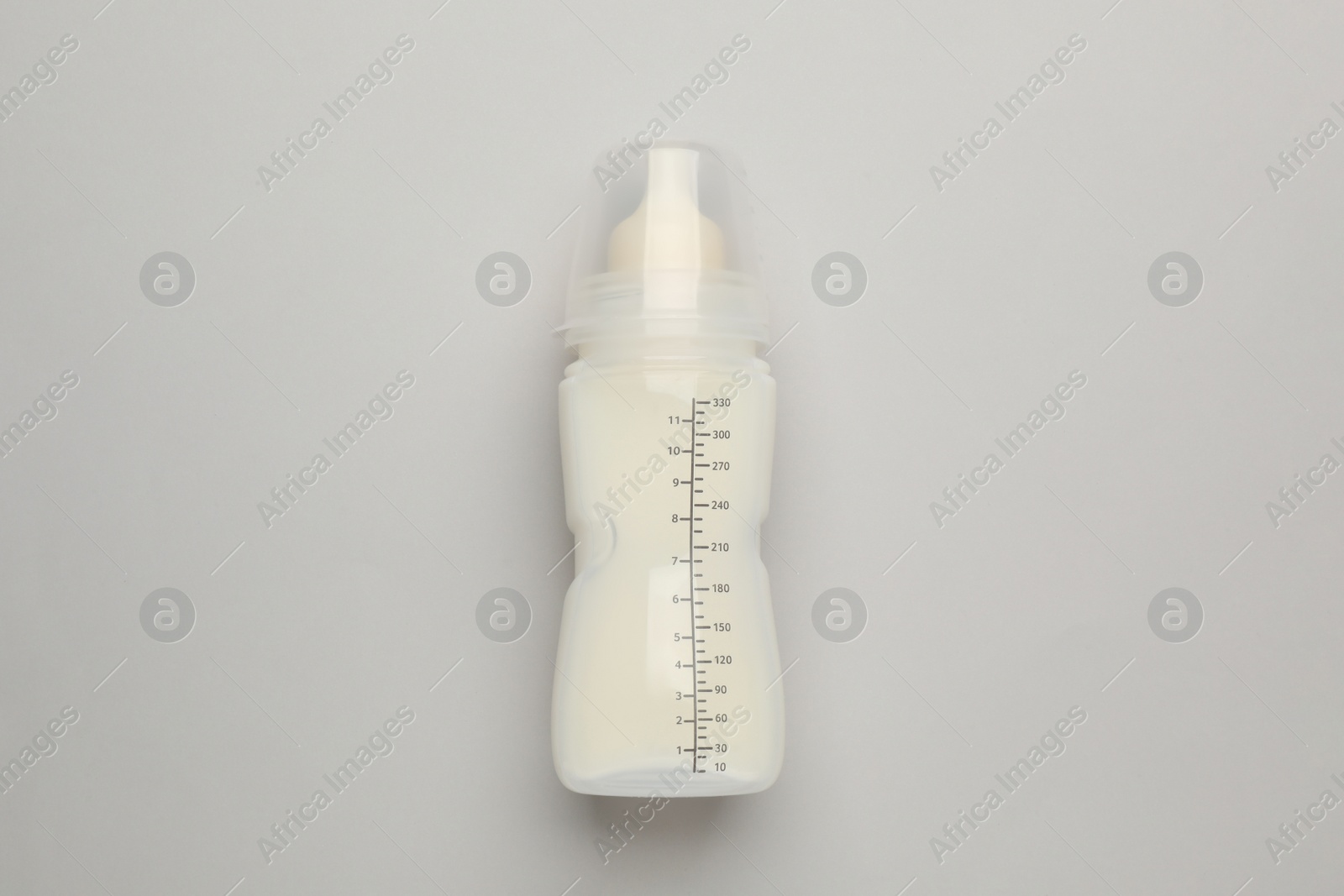 Photo of Feeding bottle with infant formula on light background, top view