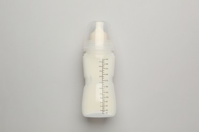 Photo of Feeding bottle with infant formula on light background, top view