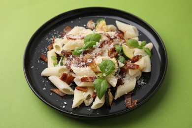 Photo of Tasty pasta with bacon and basil on light green table