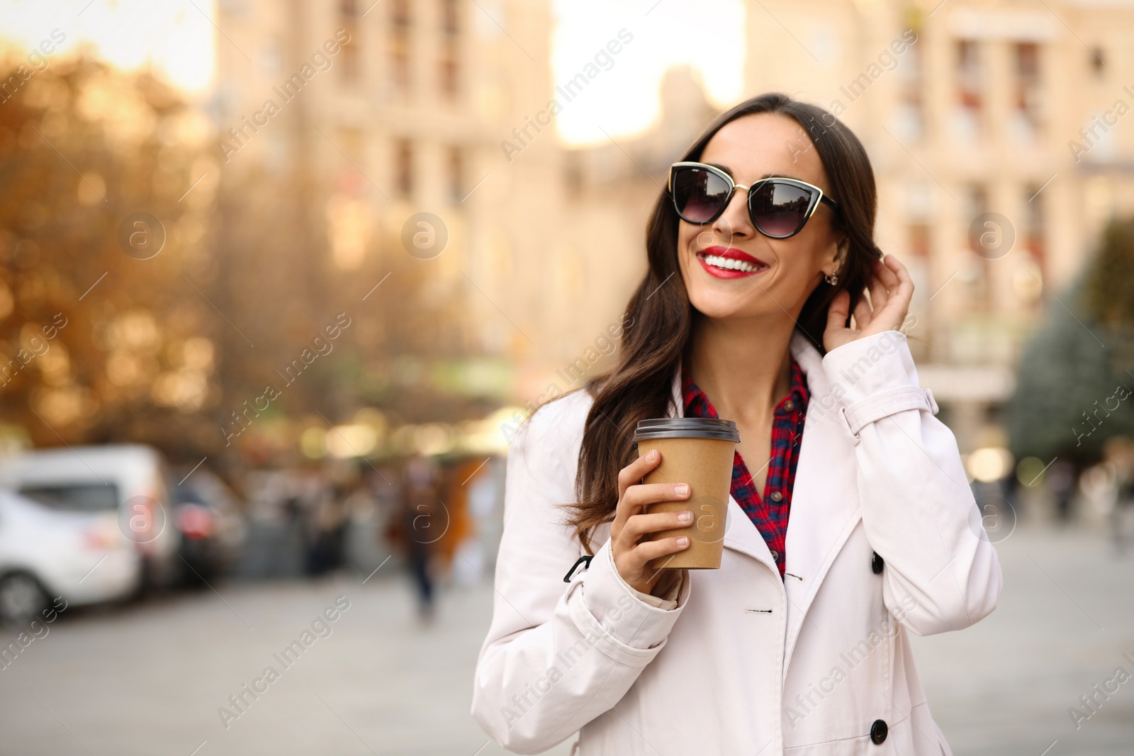 Photo of Beautiful woman with cup of coffee on city street. Autumn walk
