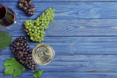 Flat lay composition with fresh ripe juicy grapes on blue wooden table. Space for text