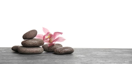 Photo of Orchid flower with spa stones on table against white background