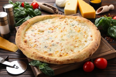 Photo of Delicious cheese pizza and ingredients on wooden table