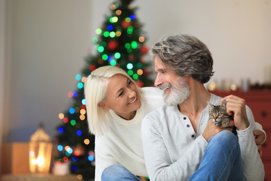 Happy couple with cute cat celebrating Christmas at home