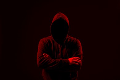 Photo of Silhouette of anonymous man on dark background, toned in red