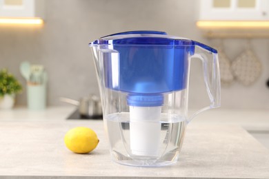 Photo of Water filter jug and lemon on light grey table in kitchen