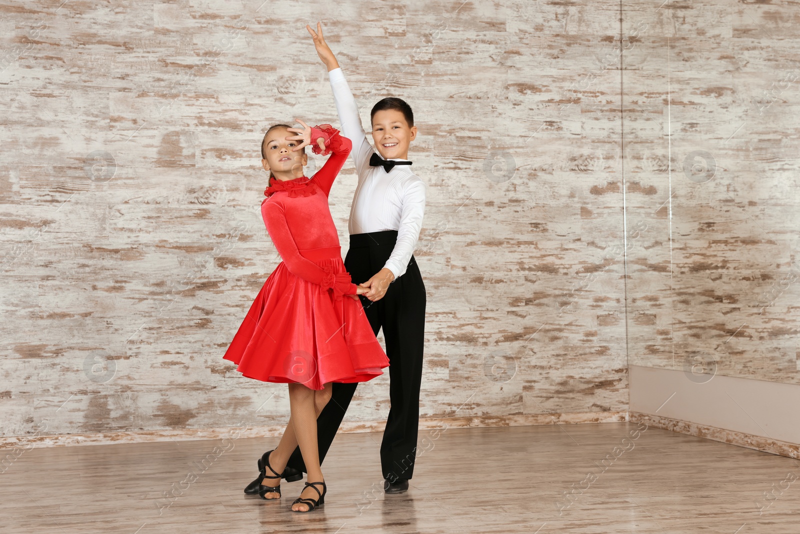 Photo of Beautifully dressed couple of kids dancing together in studio