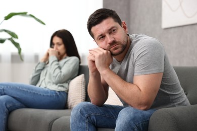 Offended couple ignoring each other after quarrel indoors, selective focus. Relationship problems