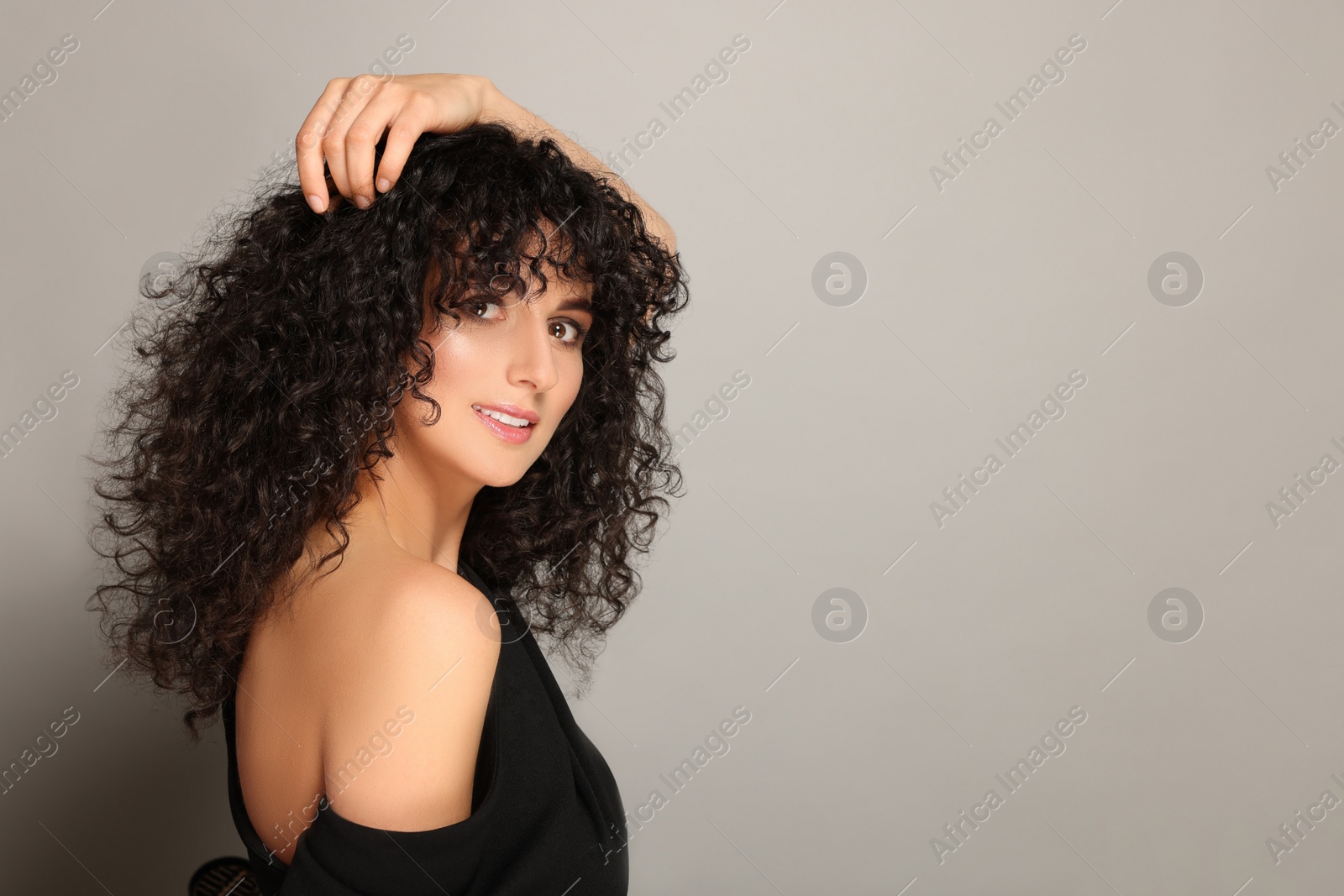 Photo of Beautiful young woman with long curly hair on light grey background. Space for text