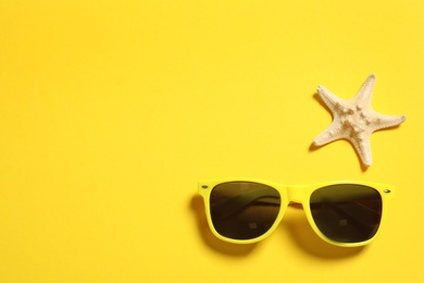 Photo of Sunglasses and starfish on color background, top view with space for text. Beach accessories