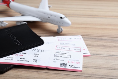 Photo of Avia tickets, passports and plane on wooden table, closeup. Travel agency concept