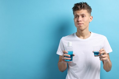 Photo of Young man using mouthwash on light blue background, space for text