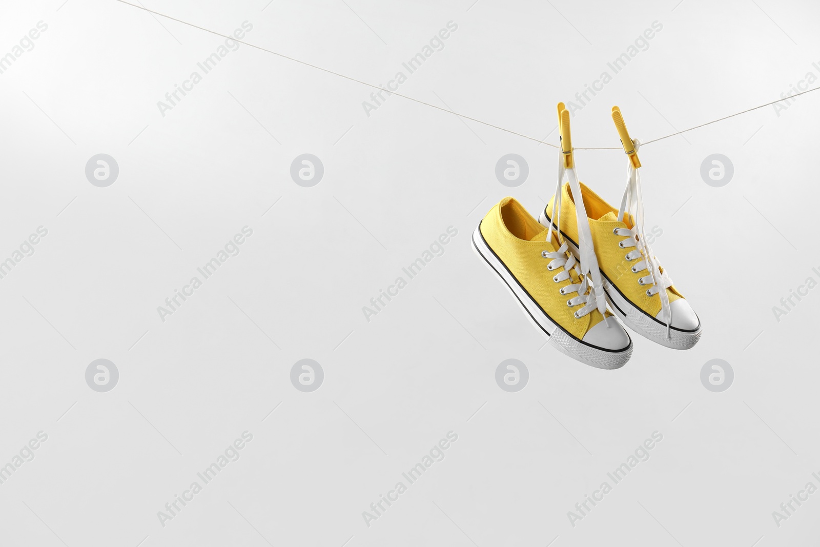 Photo of Stylish sneakers drying on washing line against light grey background, space for text