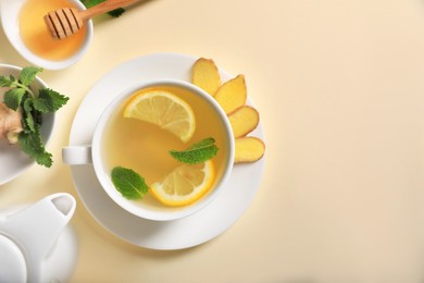 Photo of Delicious ginger tea and ingredients on beige background, flat lay. Space for text