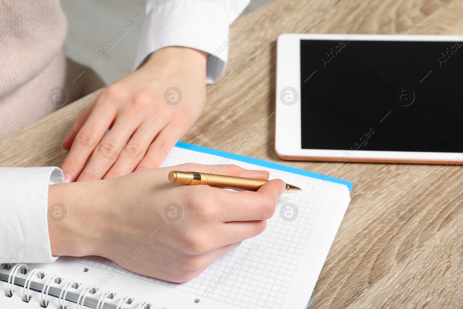 Photo of Woman taking notes at wooden table, closeup