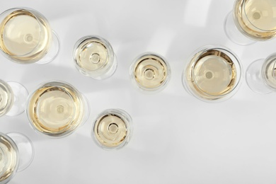 Glass of expensive white wine on light background, top view