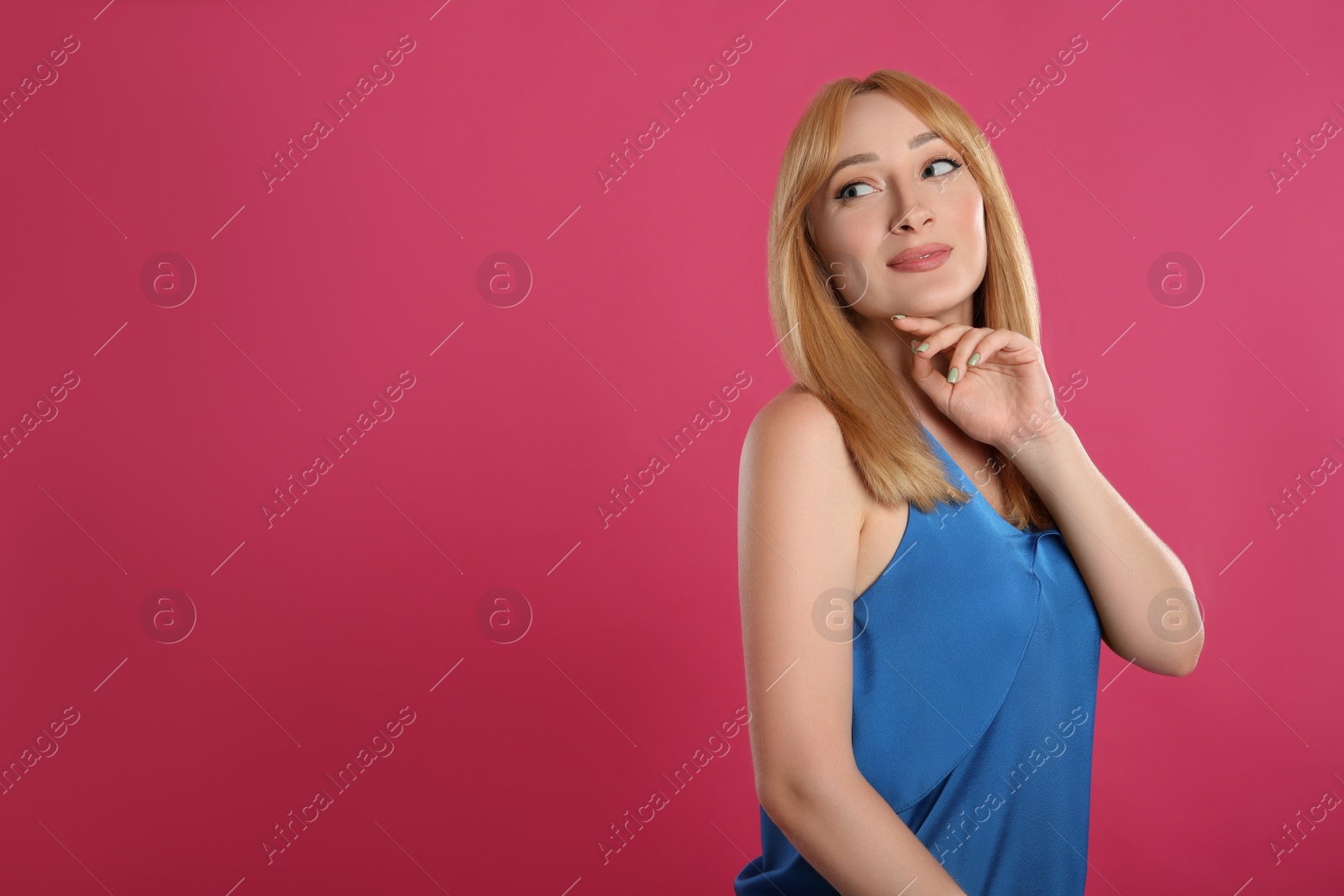 Photo of Beautiful young woman with blonde hair on pink background. Space for text