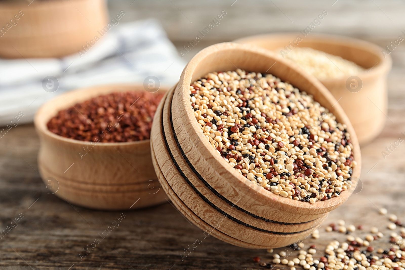 Photo of Bowl with mixed quinoa seeds on wooden table