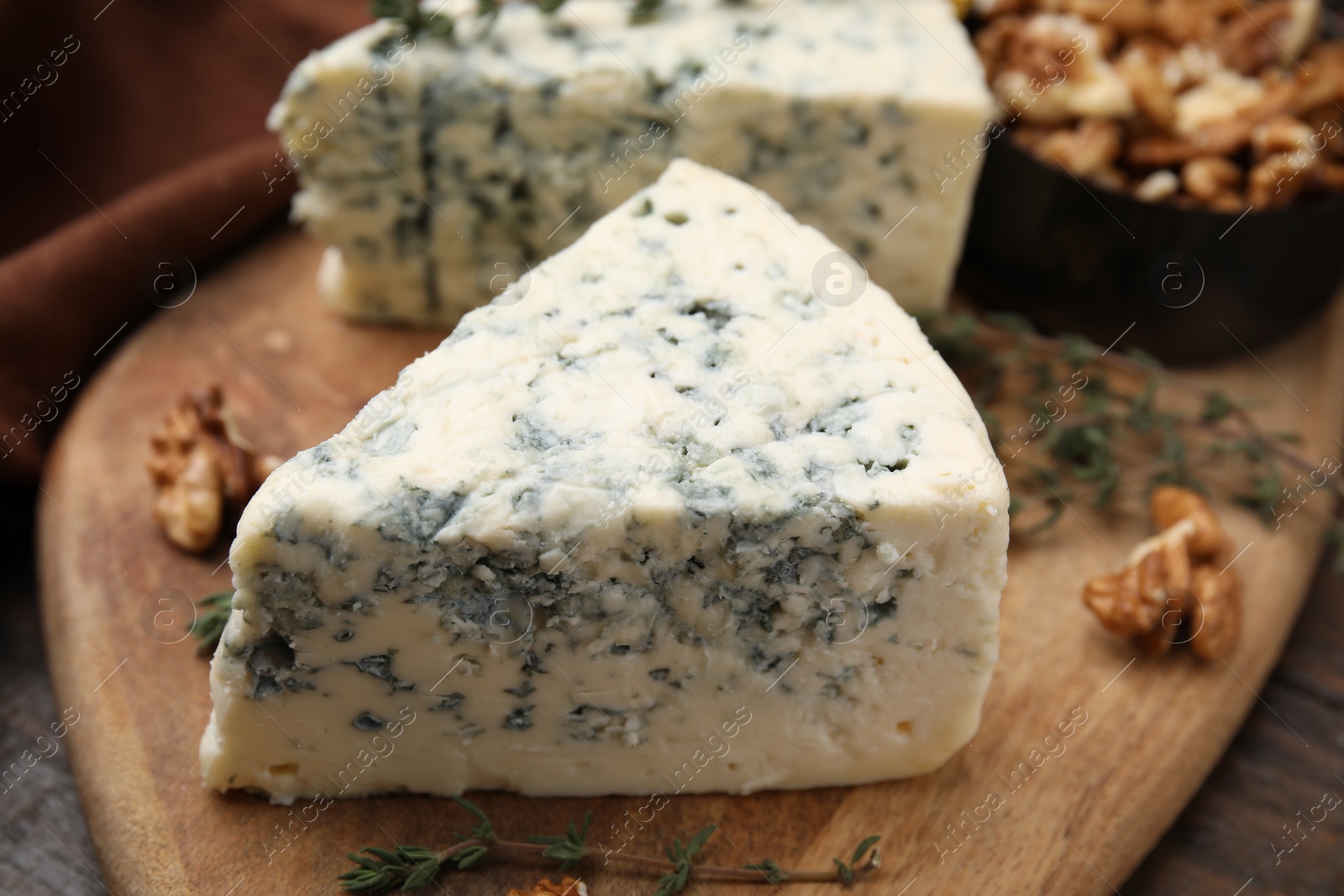 Photo of Tasty blue cheese with thyme, honey and walnuts on wooden table, closeup