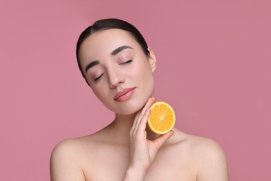 Beautiful young woman with piece of orange on pink background