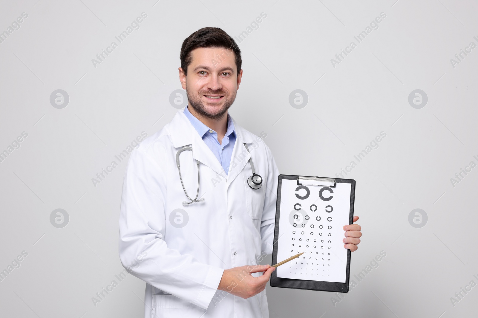 Photo of Ophthalmologist pointing at vision test chart on light background