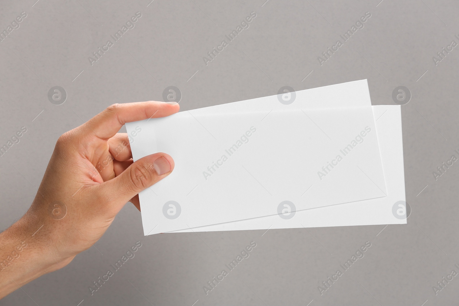 Photo of Man holding flyers on grey background, closeup. Mockup for design