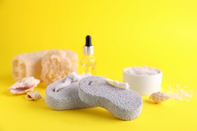 Photo of Pumice stones, cosmetic products and seashells on yellow background