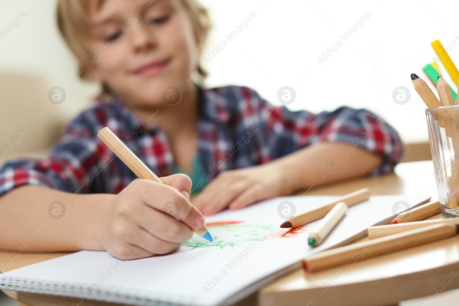 Photo of Little boy drawing at table indoors, focus on hand. Creative hobby