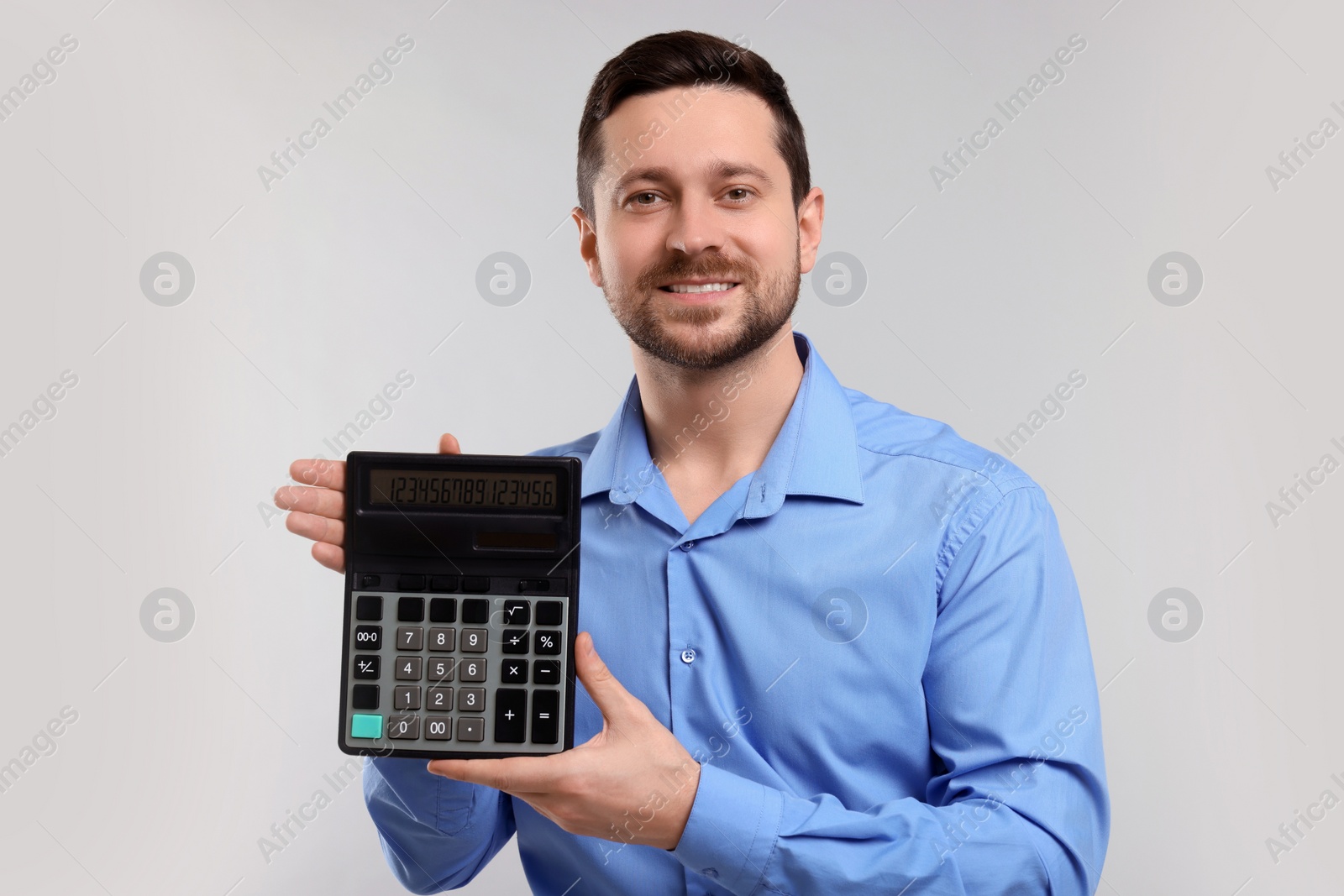 Photo of Happy accountant showing calculator on light grey background