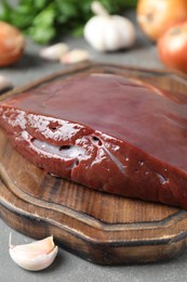 Photo of Piece of raw beef liver and products on grey table, closeup