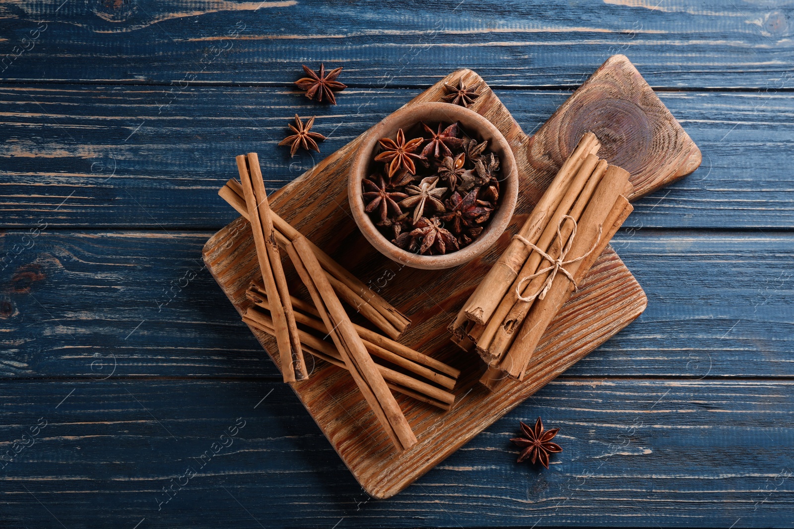 Photo of Aromatic cinnamon sticks and anise on blue wooden table, flat lay