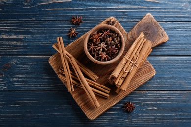 Aromatic cinnamon sticks and anise on blue wooden table, flat lay