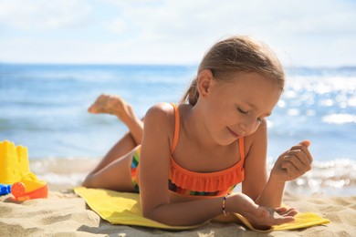 Photo of Little girl playing with sand on beach near sea