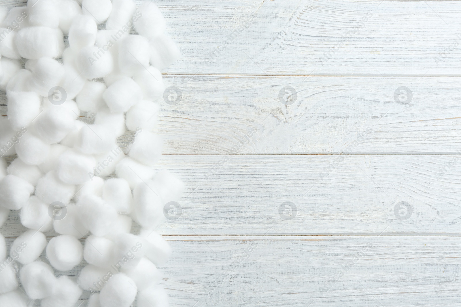 Photo of Many cotton balls and space for text on white wooden background, top view