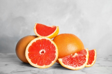 Photo of Fresh tasty grapefruits on table against light background