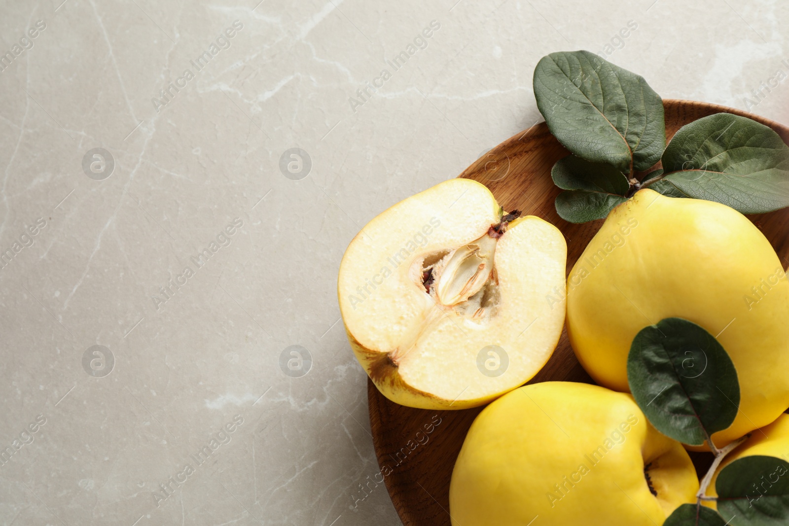 Photo of Fresh ripe organic quinces with leaves on light table, top view. Space for text