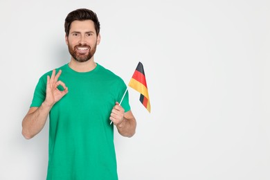 Man with flag of Germany showing ok gesture on white background, space for text
