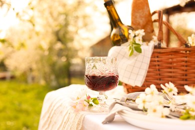 Photo of Stylish table setting with beautiful spring flowers and wine in garden