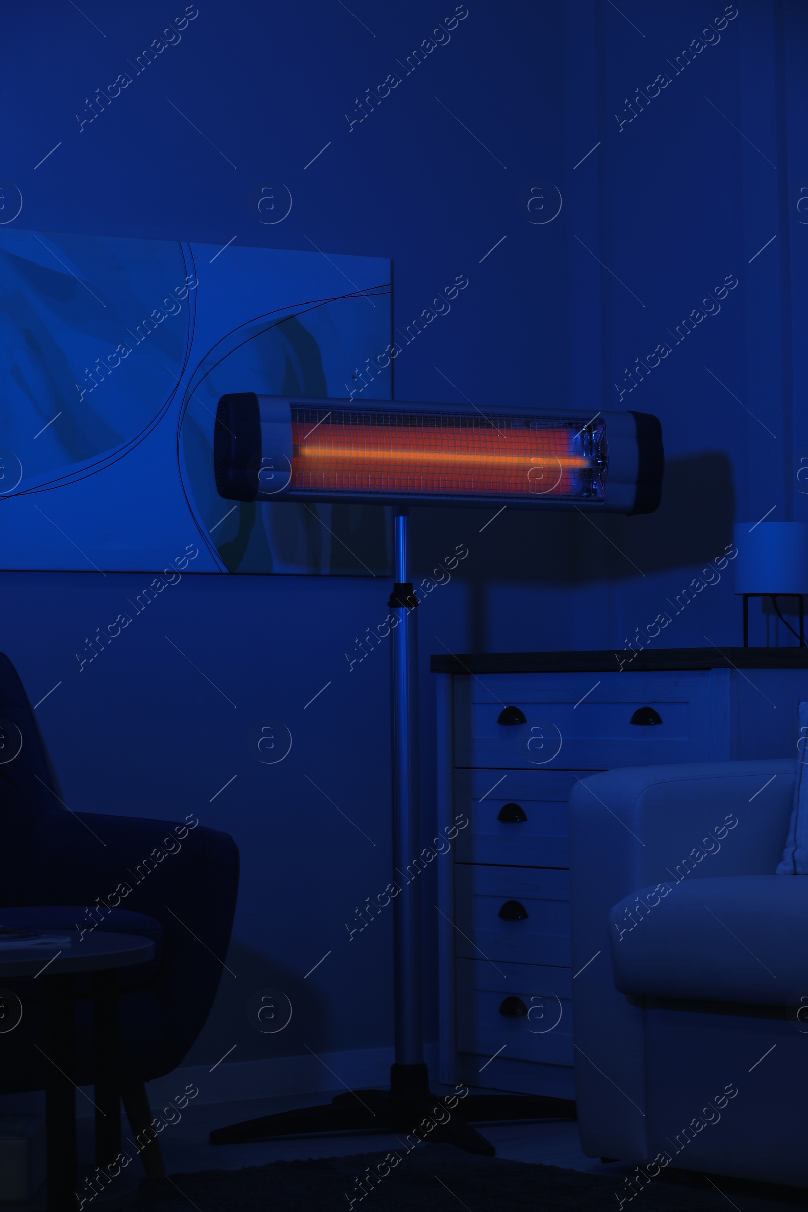 Photo of Electric infrared heater in dark living room at night