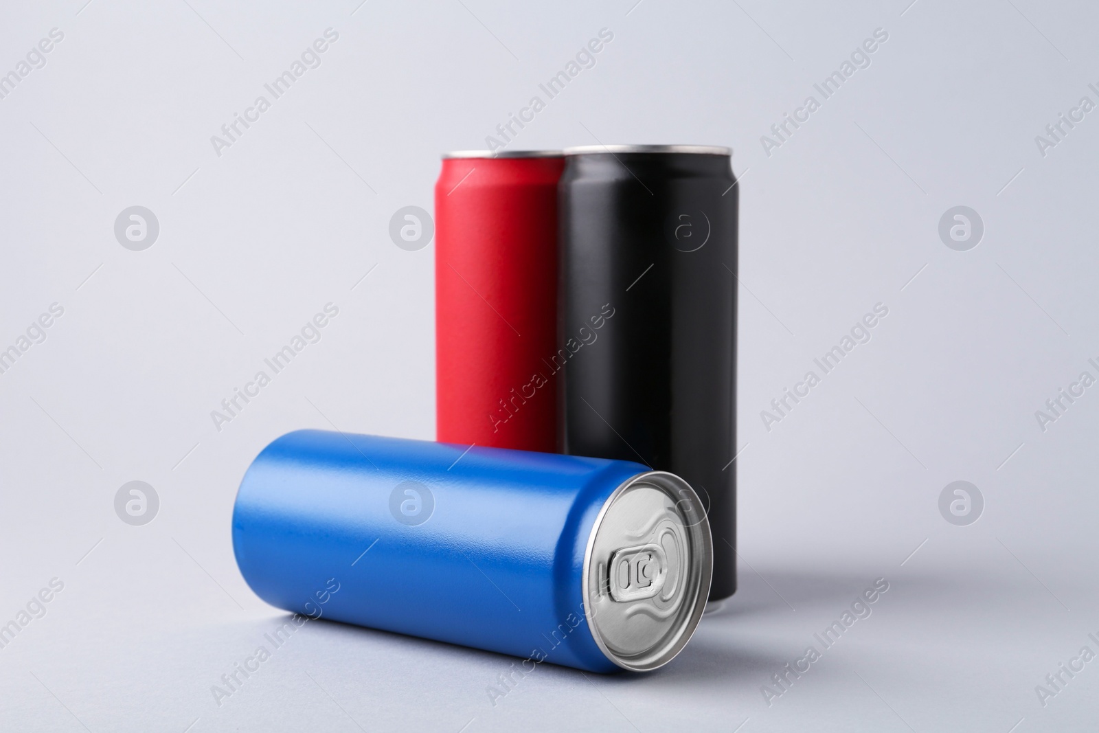 Photo of Energy drinks in colorful cans on light grey background